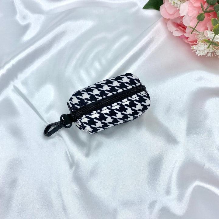 Designer houndstooth-patterned poop bag dispenser with purple details, blending practicality with unique design